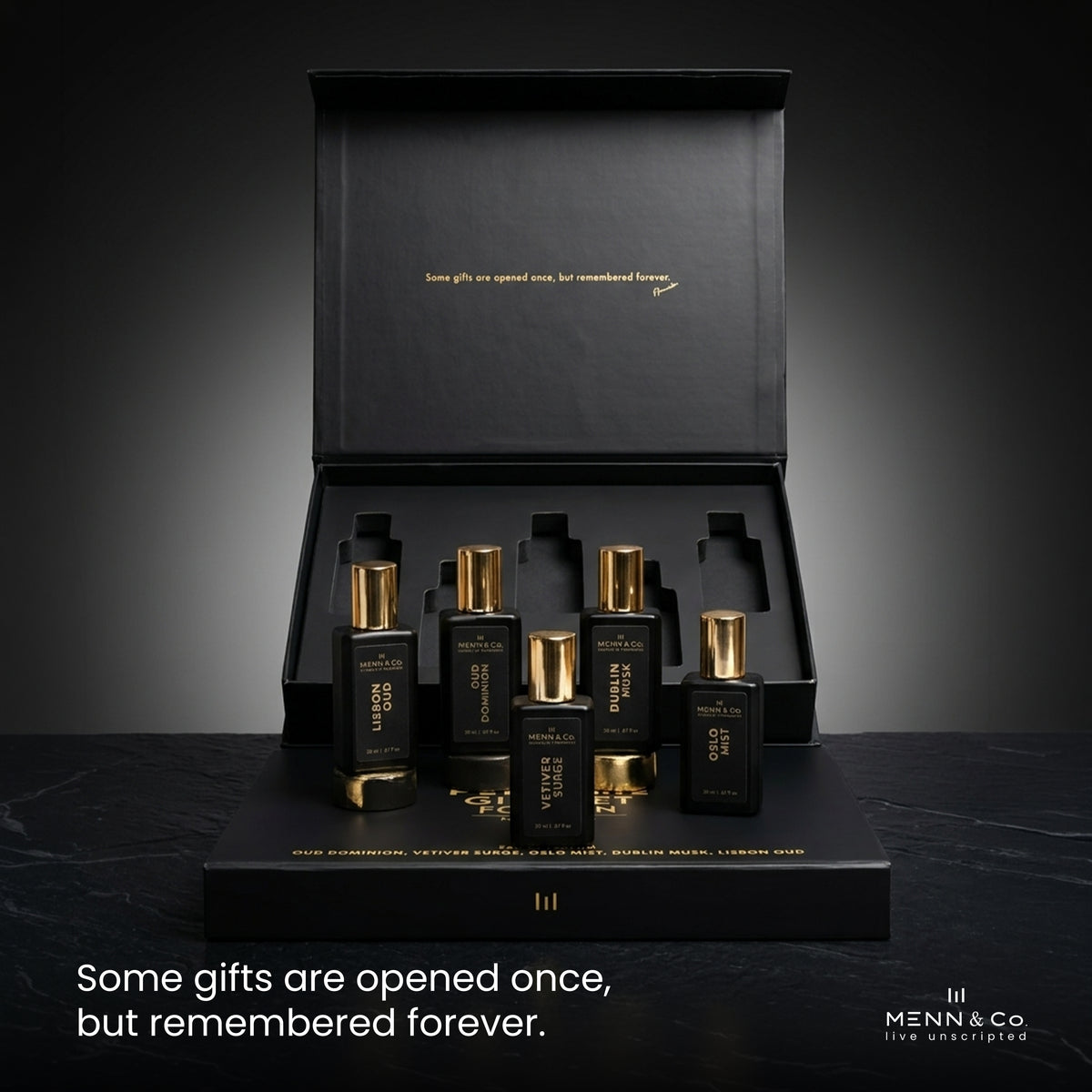 Set of black and gold perfume bottles with a black box on a dark background, featuring Menn & Co branding.