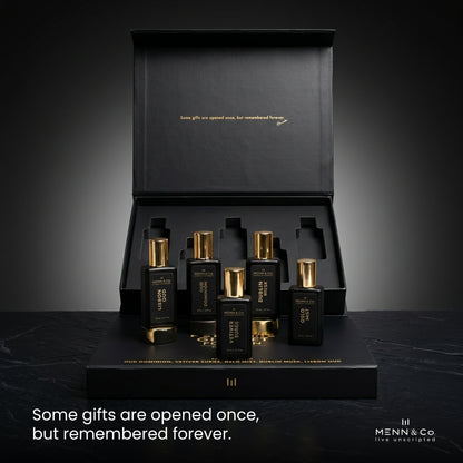 Set of black and gold perfume bottles with a black box on a dark background, featuring Menn & Co branding.