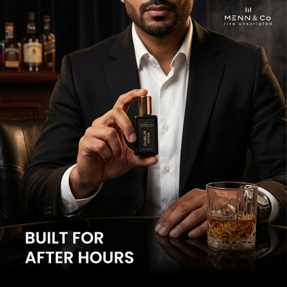 Man holding a bottle of Menn & Co. perfume with a glass of whiskey on a dark background