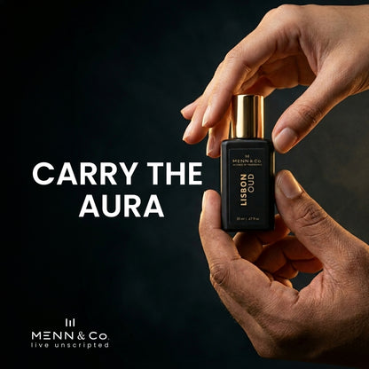 Hand holding a Menn & Co perfume bottle with text 'Carry the Aura' on a dark background