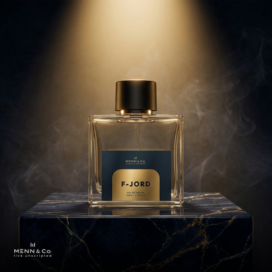 Perfume bottle labeled 'F-Jord' by Menn & Co on a dark marble surface with a warm glow.