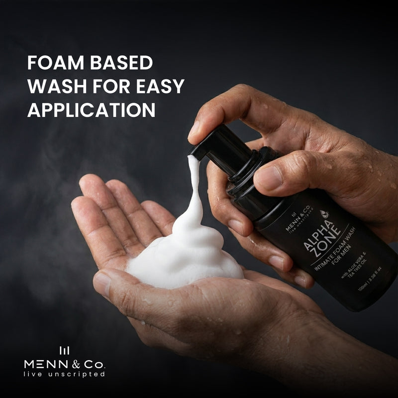 Hand holding a bottle of Menn & Co Alpha Zone wash with foam being dispensed onto another hand against a dark background.