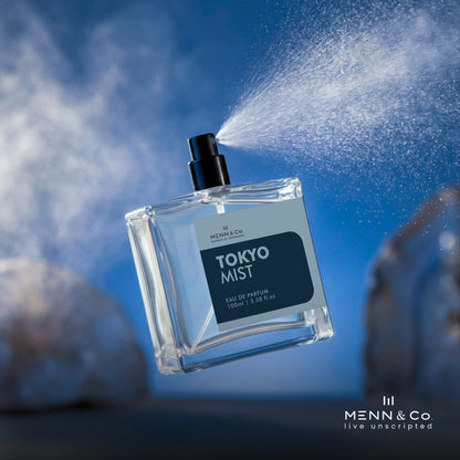 Menn & Co Tokyo Mist perfume bottle being sprayed against a blue background