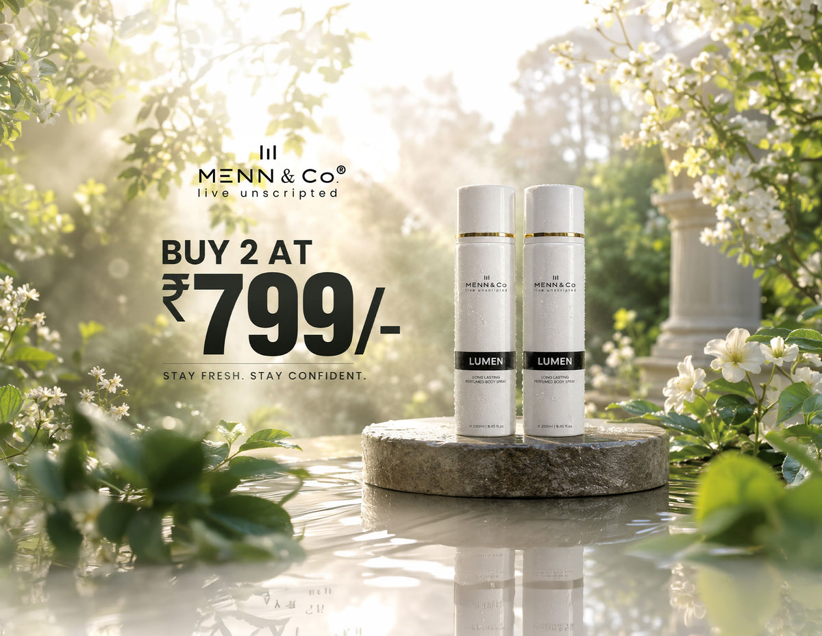 Two white Menn & Co Lumen skincare bottles displayed on a stone pedestal in a sunlit garden setting with water and white blossoms. Promotional text on the left reads 'BUY 2 AT ₥799/-'.
