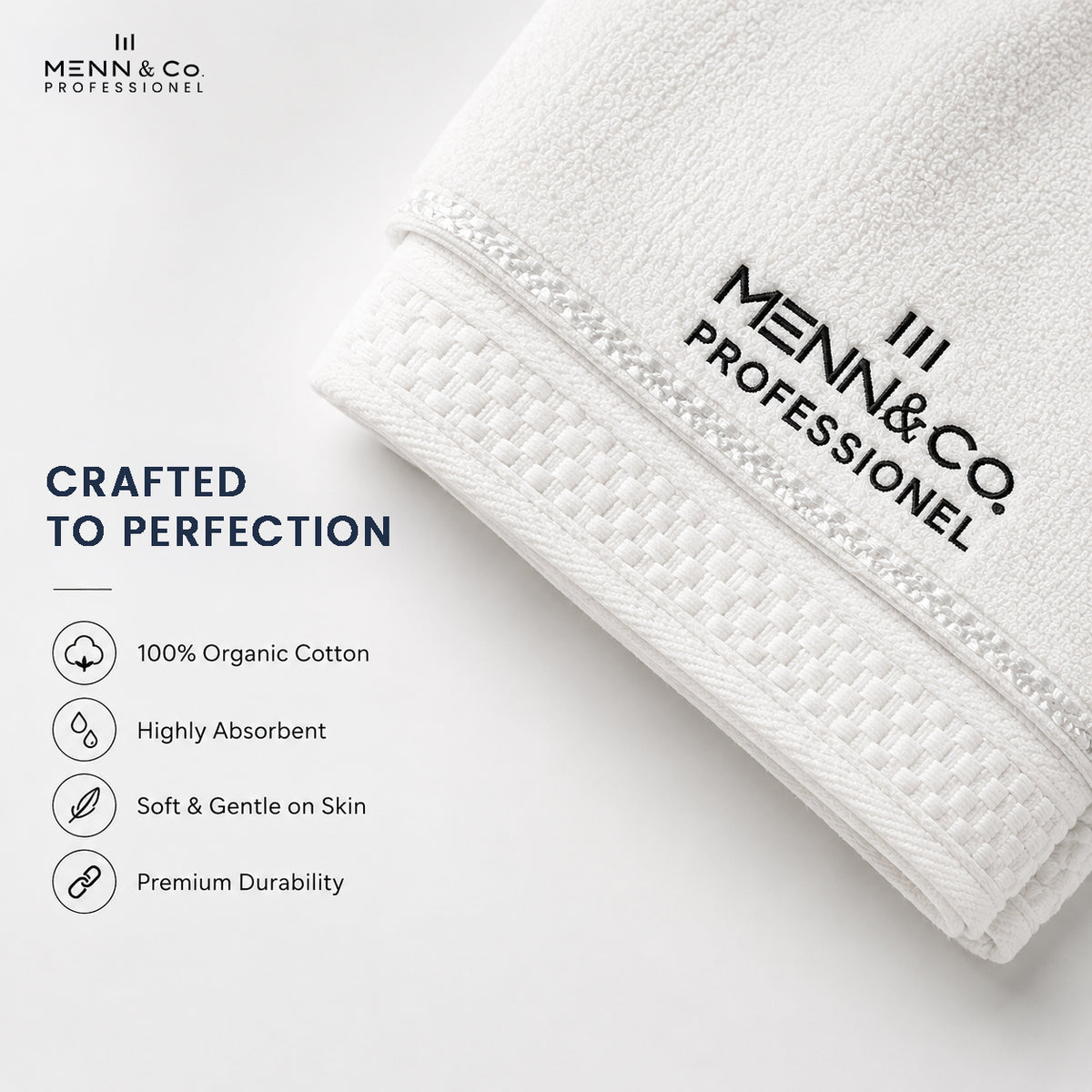 A folded white cotton towel with black printed Menn & Co Professional branding, shown on a clean white background with marketing text highlighting organic cotton, absorbency, softness, and durability.