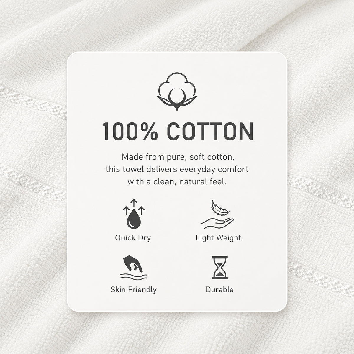 A white product information card on a white towel background, with text reading '100% COTTON' and small icons for Quick Dry, Light Weight, Skin Friendly, and Durable.